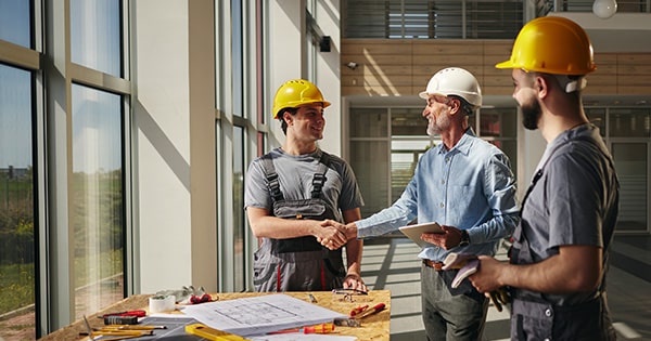 An architect shakes hands with construction workers